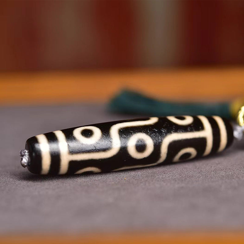 Close up of 9-eye dzi bead pendant on turquoise Tibetan mala