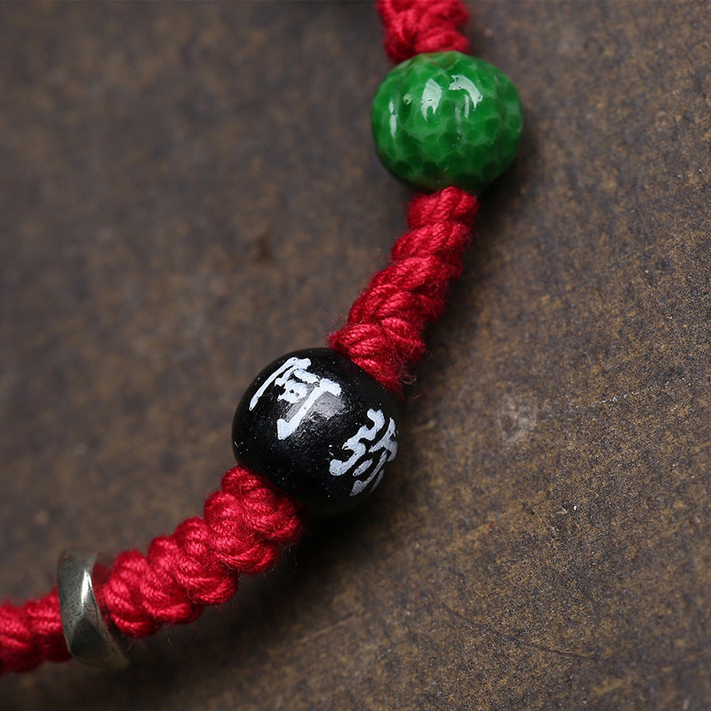 Close-up of Tibetan Silver Gau pendant featuring Medicine Buddha, antique finish amulet box on red cord bracelet
