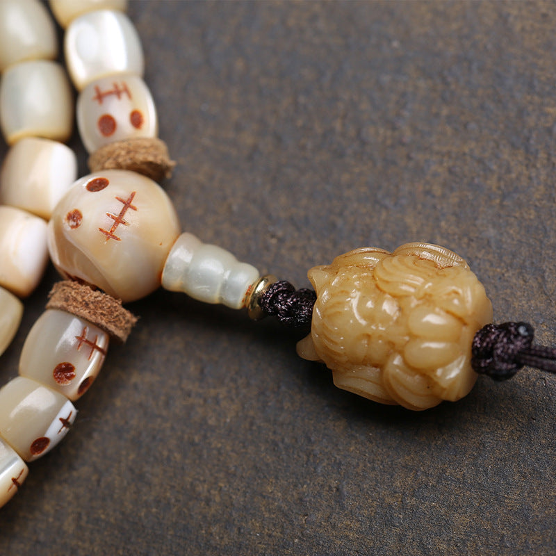 Close-up of smooth 6x6mm natural bone beads and hand carved vintage bone pendant on Tibetan 108 mala bracelet