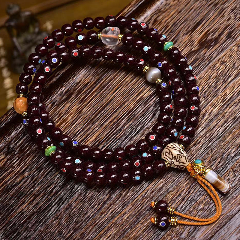 Natural Cinnabar Star Seed Bodhi Mala — 108 Bead Meditation Bracelet on a wooden surface.
