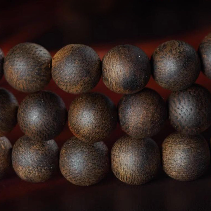 Close-up of agarwood beads showing natural wood grain and rich dark color