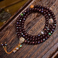 Natural Cinnabar Star Seed Bodhi Mala — 108 bead meditation bracelet with colorful accents on a wooden surface.