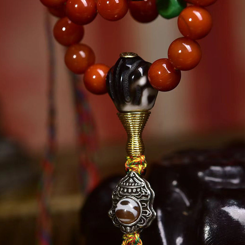 Tibetan dzi guru bead and metal hardware detail on red agate mala