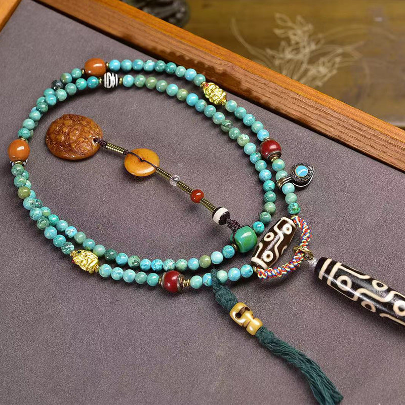 Carved Yellow Jambhala backdrop detail on turquoise prayer mala